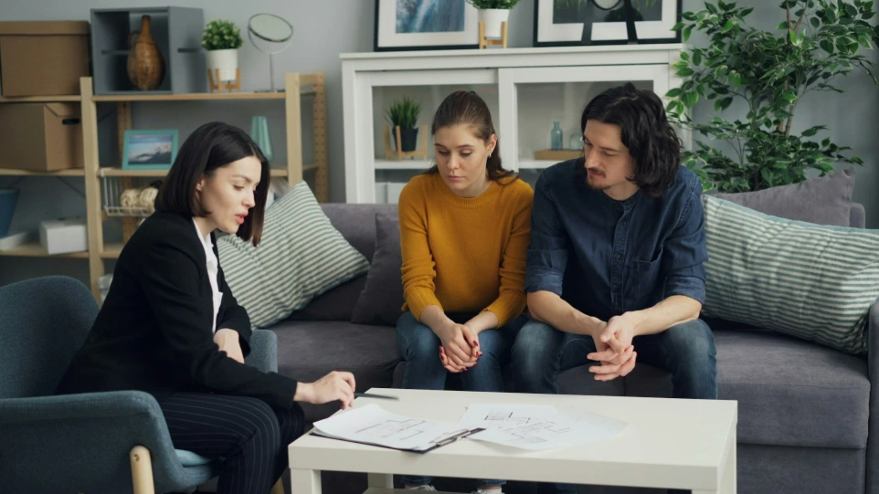 three people sitting on a couch in a living room